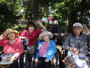 入居者が屋外で帽子をかぶり、スタッフと一緒に過ごす日中活動の様子